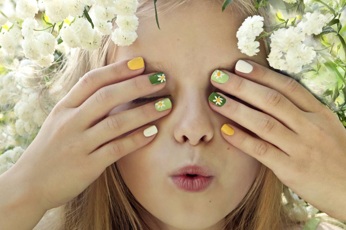 Kind mit bunten Nägeln und Blumen
