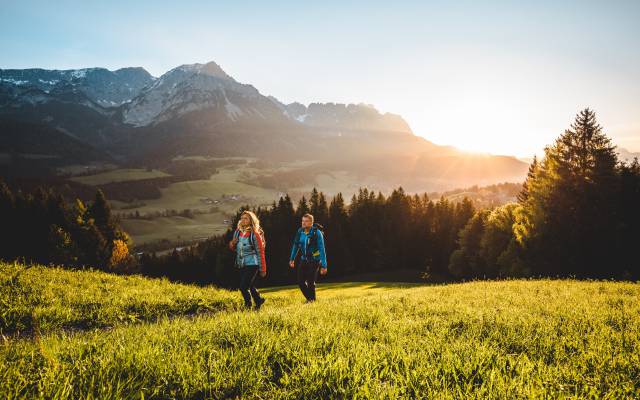 Wandern über Almwiesen bei Sonnenaufgang